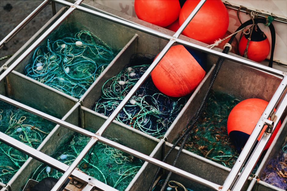 Close-up of fishing nets and buoys in metal compartments, symbolizing maritime industry.